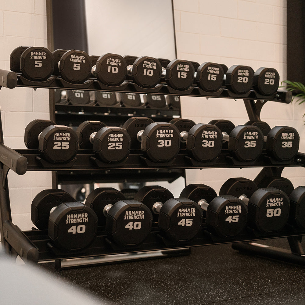 Dumbbell rack with weights labeled from 5 to 50 pounds in a gym setting.