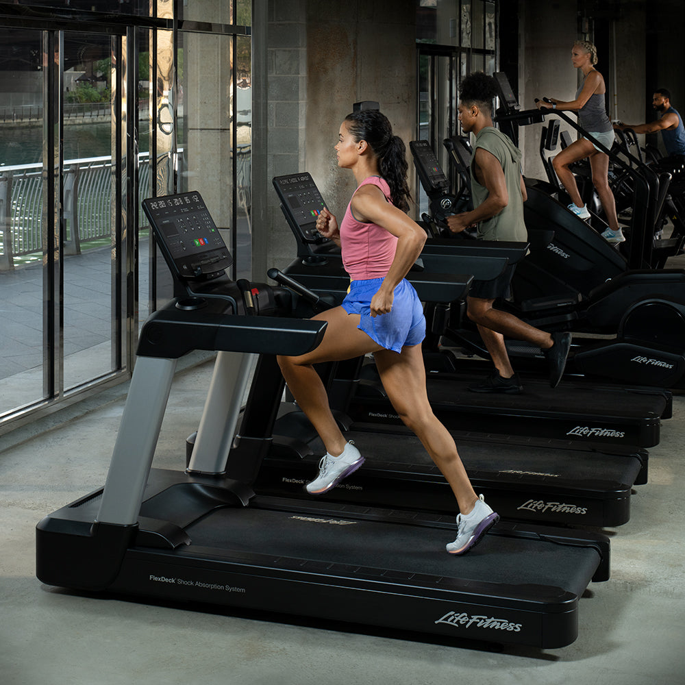 Female running on Integrity Treadmill at gym, other exercisers in background