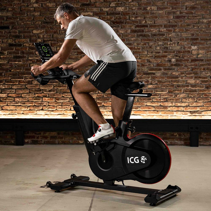 Man pedaling on IC5 Indoor Cycle with exercise data from ICG App on tablet