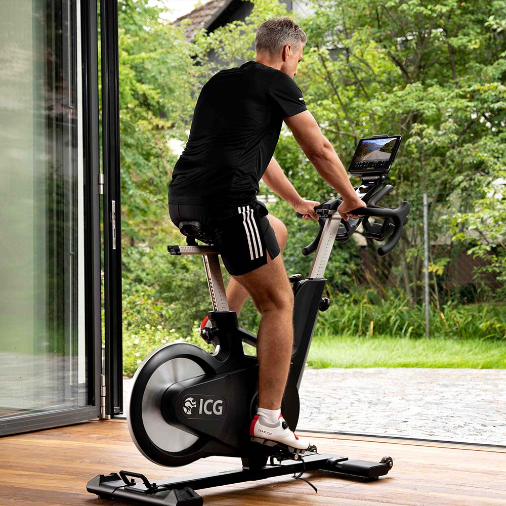 Man pedaling on Ride CX exercise bike while facing patio door